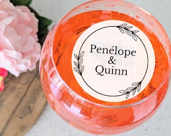 May include: A white round sticker with black text and a simple floral design. The sticker says "Penelope & Quinn".
