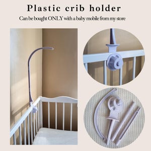 May include: A plastic crib holder in a light purple color. The holder is designed to attach to a crib and support a baby mobile. The image shows the holder attached to a white crib and also disassembled.