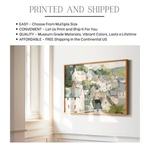 May include: A framed landscape painting of a village with white buildings and green trees. The artwork is in a wooden frame and hangs on a white wall. The text "PRINTED AND SHIPPED" is at the top.