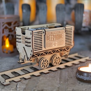 May include: A wooden model train car with a 'Beer Mine' logo and a 'Beer Mining Inc.' label. The car is on a wooden track and has wheels.