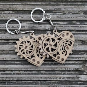 May include: Wooden keychains with a heart-shaped design and gear accents. The keychains are engraved with the phrase "Every moment with you is a treasure." The keychains are attached to silver key rings.