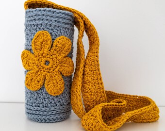 Handmade crochet bottle holder in neutral colors garnished with a flower