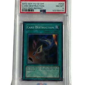 Könnte beinhalten: Eine Yu-Gi-Oh!-Karte "Card Destruction", bewertet mit NM-MT 8, in einer Schutzhülle. Die Karte zeigt einen dunklen Hintergrund mit schwebenden Kartenbildern und dem Text "CARD DESTRUCTION" und "[SPELL CARD]" auf Englisch. Die Karte ist ein DMG-Nachdruck von 2003.