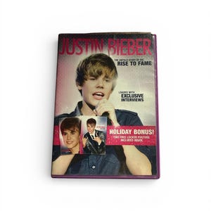 Könnte beinhalten: Ein Buch mit dem Titel "JUSTIN BIEBER: THE UNTOLD STORY OF HIS RISE TO FAME." Das Cover zeigt ein Foto von Justin Bieber und enthält den Text "LOADED WITH EXCLUSIVE INTERVIEWS" und "HOLIDAY BONUS! TWO FREE LOCKER POSTERS INCLUDED INSIDE."