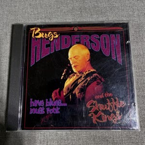May include: A Bugs Henderson and the Shuffle Kings CD case. The cover features a portrait of a man with the band's name in purple and the text "have blues... must rock" in purple.