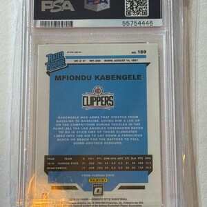 May include: A basketball trading card of Mfiondu Kabengele in a PSA holder. The card features the Clippers logo and player stats. The card is from the 2019-20 Panini Donruss Optic Basketball series. The card is in a clear plastic case.