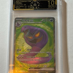 May include: A graded Pokémon card featuring a purple Arbok ex character with a green and gold holographic background. The card is encased in a clear plastic holder with a Pristine 10 grade. Text includes "2025 Pokemon CHN" and "177/151 SR".
