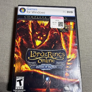 Op de afbeelding: PC DVD-gamecase voor "The Lord of the Rings Online: Mines of Moria". De cover toont een vurige illustratie van een demonische figuur en een tovenaar. De game is door de ESRB beoordeeld als Teen en vereist een internetverbinding.