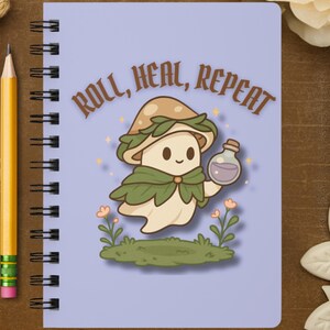 May include: A light purple spiral-bound notebook with a cartoon mushroom character holding a potion bottle. The cover has the text "ROLL, HEAL, REPEAT" above the character. The design includes green grass, flowers, and a brown mushroom cap.