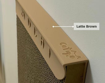 Puede incluir: Un rascador para gatos de cartón beige con una parte superior Latte Brown. La parte superior tiene las palabras "Catnip" y "Scratch" grabadas. El rascador tiene una superficie texturizada y está diseñado para que los gatos se rasquen.