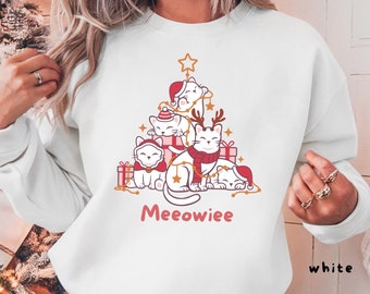May include: White sweatshirt featuring a Christmas tree design made of cartoon cats wearing festive accessories. The word "Meeowiee" is written in pink script below the cats. The sweatshirt is available in 6 sizes and 14 colors.