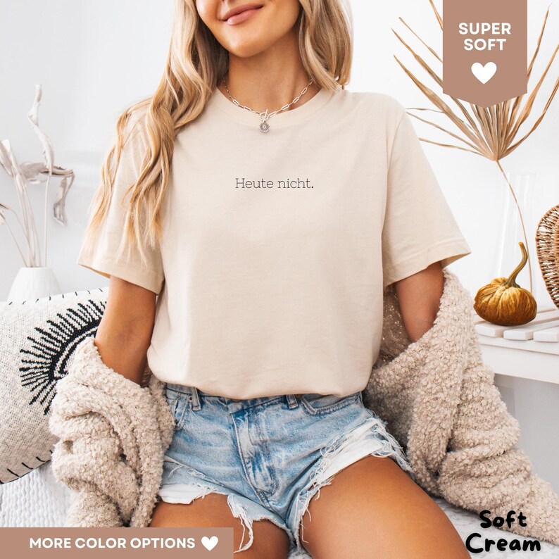 May include: A soft cream-colored t-shirt with the German phrase "Heute nicht" printed in black. The shirt is short-sleeved and has a relaxed fit. The words "Super Soft" and "Soft Cream" are also visible in the image.