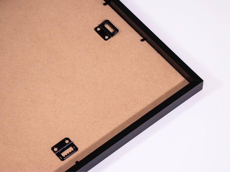 May include: Black picture frame with a brown cardboard backing and two metal hanging clips.