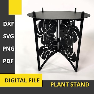 May include: Black plant stand with a round top and three legs. The legs are decorated with a cut-out design of tropical leaves.