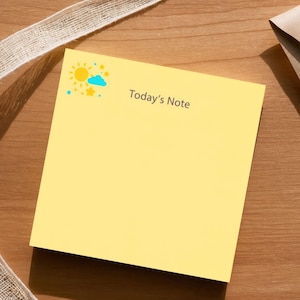 May include: A yellow sticky note with the text "Today's Note" and a weather icon, next to a brown paper envelope and a white ribbon on a wooden surface. The weather icon includes a sun, cloud, and star.