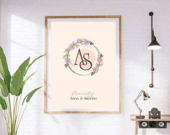 May include: A framed print with a peach background featuring a floral wreath with the letters "AS" in the center. The text "family Anna & Simone" is below the wreath.