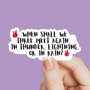 Puede incluir: Pegatina blanca con texto negro que dice "WHEN SHALL WE THREE MEET AGAIN, IN THUNDER, LIGHTNING, OR IN RAIN?" con un cerdo de dibujos animados rojo en cada extremo.