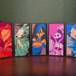 May include: Five framed art prints with abstract figures in vibrant colors. The artwork features a red, orange, green, blue, and pink color palette. Each piece is in a black frame, creating a cohesive display.