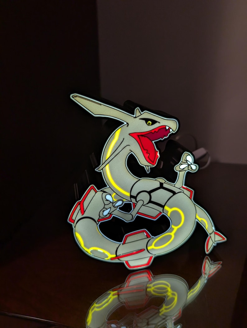 K&ouml;nnte beinhalten: Eine stilisierte, hellgraue Drachenfigur mit gelben und roten Akzenten. Der Drache hat einen langen, gewundenen K&ouml;rper und ein detailliertes Design, mit rotem Maul und gelben Highlights. Wahrscheinlich ein Sammler- oder Dekorationsartikel.