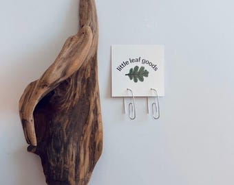 May include: A pair of silver paperclip earrings on a white card with the text "little leaf goods" and a green leaf illustration.