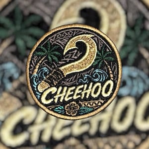May include: A circular embroidered patch featuring a gold fishhook centered over a black background with green palm trees, blue ocean waves, and a small flower. The word CHEEHOO is stitched in gold lettering across the bottom of the design.