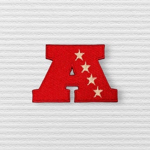May include: Red felt letter A with four white stars. The letter is a patch or applique.