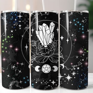 Puede incluir: Tres vasos de acero inoxidable con un diseño en blanco y negro. El diseño presenta un cristal, una flor, un pentagrama y lunas sobre un fondo de mármol negro con estrellas blancas.