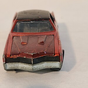 May include: A red toy car with a black roof and a silver front bumper. The car has a detailed hood with two air vents.