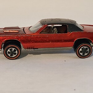 May include: A red toy car with a black roof and chrome accents. The car has a detailed interior and black wheels with red trim.