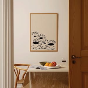 May include: A black and white illustration of five coffee cups with the text "Who wants a cuppa?" printed on a beige background. The illustration is framed in a light brown frame.
