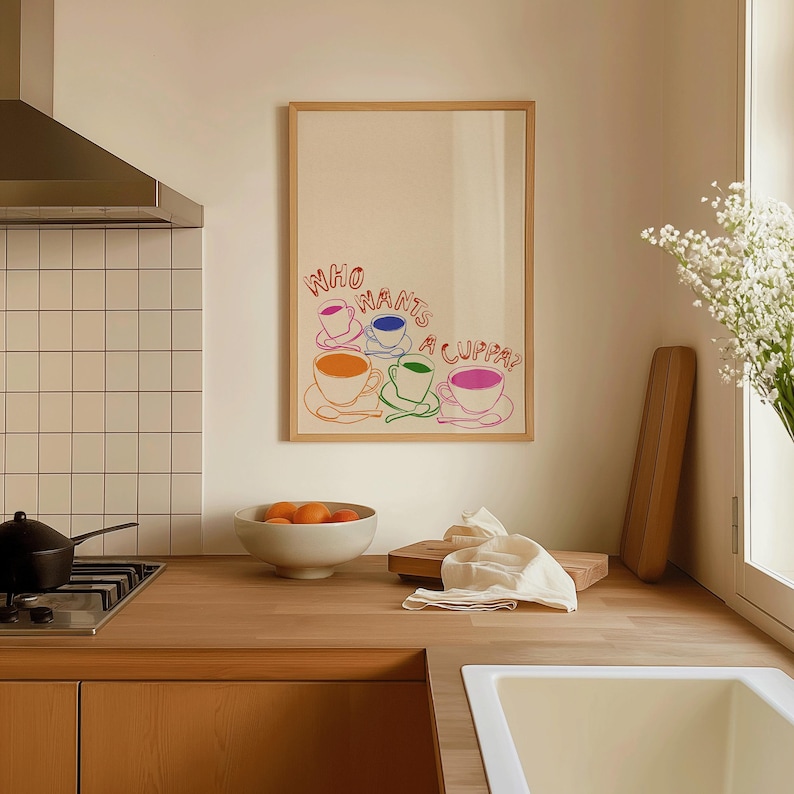 May include: A framed print with the text "Who wants a cuppa?" in rainbow colors with a graphic of five teacups in different colors.