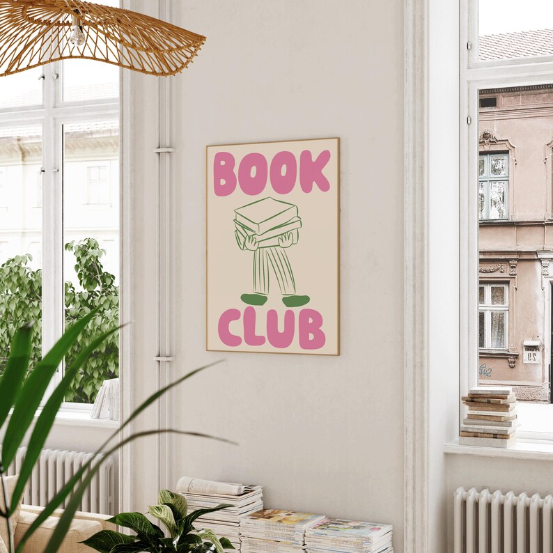 May include: A pink and green poster with the text "BOOK CLUB" in large, pink, bubble letters. A line drawing of a person carrying a stack of books on their head is in the centre of the poster.