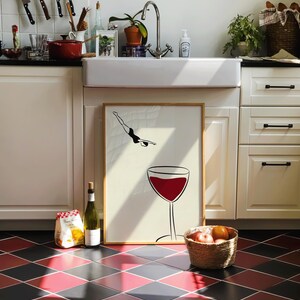 May include: A kitchen scene with a framed art print featuring a diver and a wine glass. A bottle of wine, a bag of food, and a basket of fruit are on the red and black tiled floor. Knives hang on the wall.