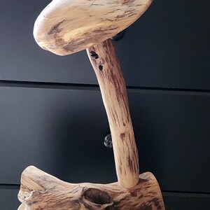 May include: A wooden mushroom lamp with a natural brown finish. The lamp is made from a single piece of wood and has a unique, organic shape.