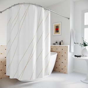 May include: White shower curtain with a gold geometric pattern of diagonal lines. The curtain is hanging in a bathroom with a white bathtub and tiled walls.