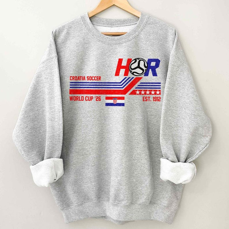 May include: A heather gray sweatshirt with a Croatian soccer design. The design includes the text "HR", a soccer ball graphic, and the words "Croatia Soccer" and "World Cup '26". The design also features the Croatian flag and the text "EST. 1912".