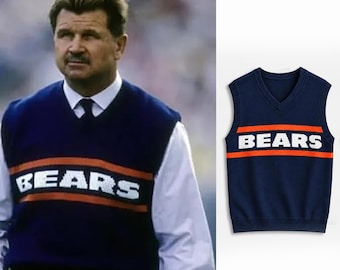 May include: A navy blue sleeveless V-neck sweater vest featuring a horizontal orange stripe across the chest with the word BEARS printed in white block letters. The knit garment has a ribbed neckline, armholes, and a ribbed hem at the bottom.