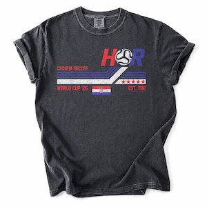 May include: Dark gray t-shirt with a graphic design featuring the text "HR", a soccer ball, and the Croatian flag. The design includes the words "Croatia Soccer", "World Cup '26", and "Est. 1912".
