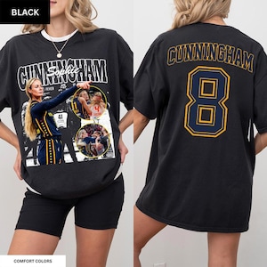 May include: A black short-sleeve t-shirt featuring a graphic print of a basketball player named Sophie Cunningham. The front displays the name CUNNINGHAM, the name Sophie, and action photos. The back features the name CUNNINGHAM and the number 8.