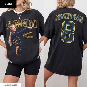 May include: A black short-sleeve t-shirt featuring a graphic of a basketball player with the text CUNNINGHAM, Sophie, and POINT GOD on the front. The back displays the name CUNNINGHAM in yellow and blue lettering above the large number 8.