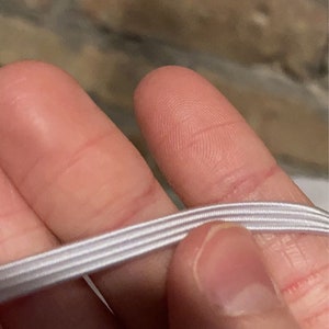 May include: White elastic string with three rows of stitching.