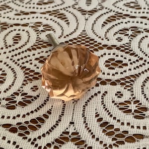May include: A pink glass cabinet knob with a faceted design and a silver screw.