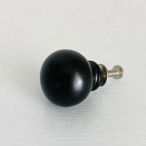 May include: A black round cabinet knob with a silver screw.