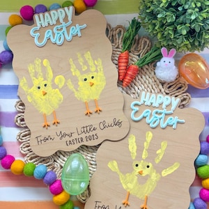 Può includere: Due cartelli di legno con disegni di pulcini fatti a mano. I cartelli sono decorati con il testo "Buona Pasqua" e "Dai tuoi piccoli pulcini Pasqua 2025".