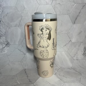 May include: A cream-colored stainless steel tumbler with a black and white design featuring Stitch and other characters from Lilo & Stitch. The tumbler has a handle and a lid with two buttons.