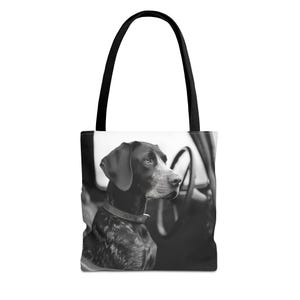 May include: Black and white photo of a dog looking out the window of a car. The dog is sitting in the passenger seat and has a black collar on. The photo is printed on a black tote bag.