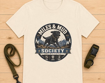 Maglietta Miles & Mud con il logo del cane da salvataggio Labrador e distintivo per avventure all'aria aperta.