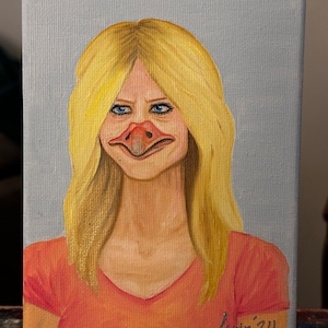 May include: A painting of a woman with a duck beak, wearing a peach-colored shirt and blonde hair. The painting is signed "Erin'24" in the bottom right corner.