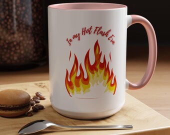 May include: White ceramic mug with a pink interior and handle. The mug features the text "In my Hot Flash Era" in red script above a flame graphic in yellow, orange, and red.