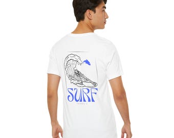 May include: White t-shirt with a graphic of a skeleton surfing on a wave with a blue fish jumping out of the water. The text "SURF THINGS U" is printed below the graphic.